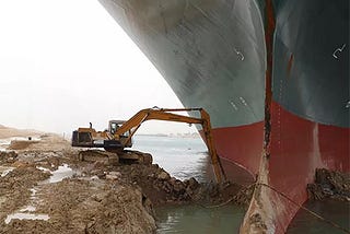 Escavadeira tenta desenterrar um navio de carga preso no Canal de Suez