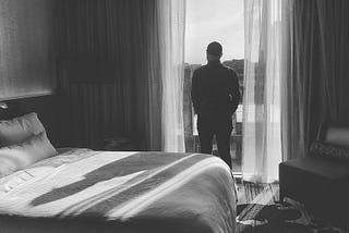 Man looking out window of hotel room