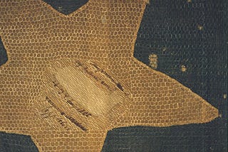 A damaged fabric panel with a gold star on a deep blue background