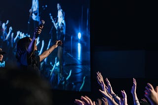 A woman in a concert with crowd lifting hands