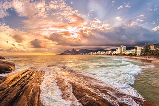 Sunset photo of Ipanema beach with color and pattern of waves mimicking clouds in the sky.