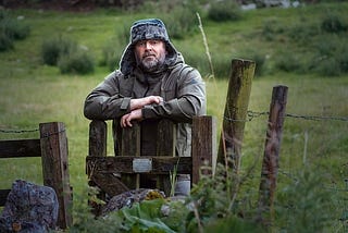 A man leaning over a small wooden fence