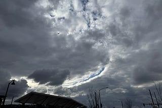 A photo of a cloudy sky, with a long arc of cloud break showing blue sky above.