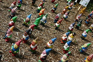 A disconcerting number of gnomes on a dirt field.