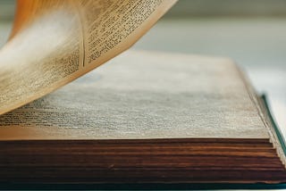 A crisp, close-up photo of a book with one page from the right side in the process of turning.