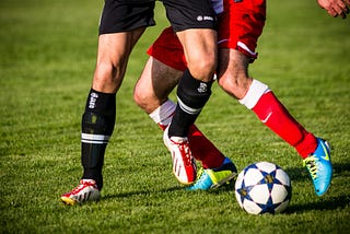 THe legs of two soccer players battling for the ball.