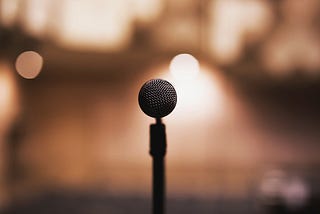A microphone sits ready on an open stage with a spotlight