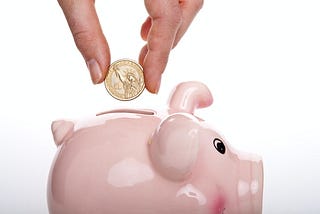 A coin in being put into a piggy bank
