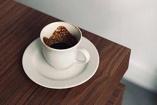 Dirty white coffee cup with a saucer on a wooden table