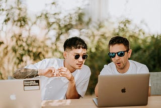 2 guys having a discussion with their laptops.