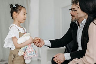 Photo of young girl standing in front of her new, adopted parents
