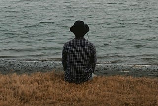 Person sitting with back to camera looking out at the water.