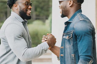 Two Black men sharing a DAP handshake