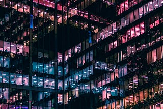 An office building lit up inside in hues of blue and pink