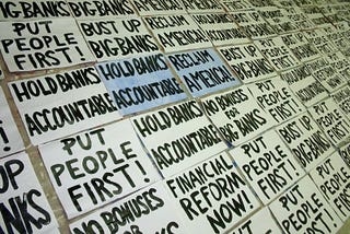 Picture of protest posters with titles such as “Hold Banks Accountable” and “Put People First!”