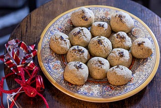 A plate of cookies sits next to a holiday bow and ribbon.