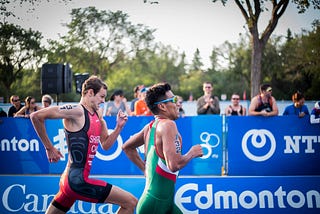 Two people running in a race, striving for the finish line in front of a crowd of people