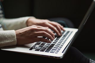 Person writing a mental health article on a laptop as a paid assignment for Monarch.