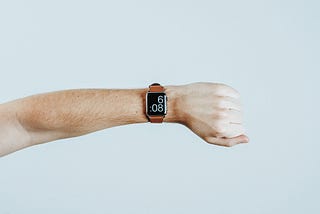 Caucasian person’s left arm, wearing a smartwatch reading 6:08. Alex2Cents.com.