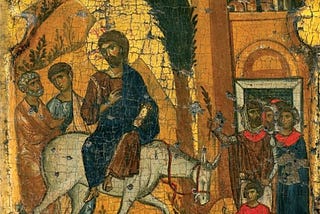 An icon, paint on wood. Jesus on a donkey entering Jerusalem. His disciples stand alongside his path as he enters the city.