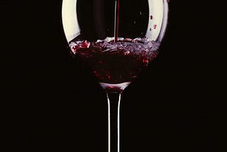 Wine pours into a crystal clear glass on an all black background
