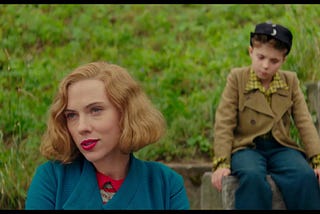 Rosie (Scarlett Johansson) and Jojo (Roman Griffin Davis) in the same shot, while the former sits in the front, and the latter sits behind