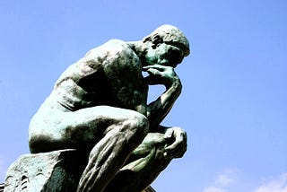 Statue of The Thinker with the sky in the backdrop.