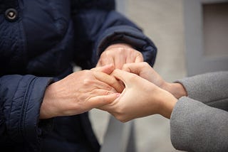 Older person holding hands with younger person