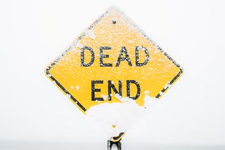 Yellow “DEAD END” road sign with a dusting of snow.