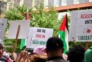 Protest for Palestine in Tiohtiè:ke/Montreal with many protest signs and Palestinian flags. In the background, you can read a sign that says: “End the siege on Gaza Now!” Photo by Nelly Bassily