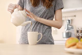 Woman pouring tea from tea pot.