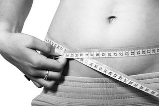 a woman measuring her waiste after doing a diet