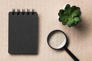 A notebook, a magnifying glass and a succulent on top of a Braille textured sheet. (Freepik)