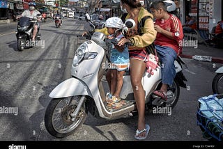 This biker is pausing before pulling into traffic from a soi.