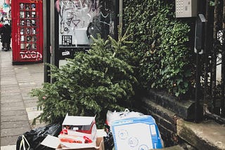 bags and boxes of waste sitting beside a Christmas tree