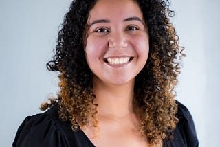 An image of Alaa Mohammed wearing a black blouse smiling with a light background