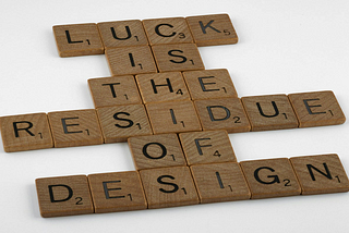 Scrabble tiles spelling out a quote from English poet John Milton, “Luck is the residue of design”. It is a key theme of the article.