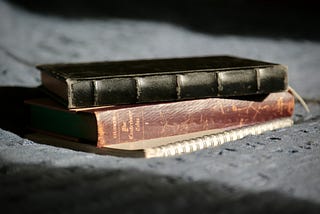 Three worn books sit in a stack.