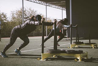 Women training by pushing heavy weights