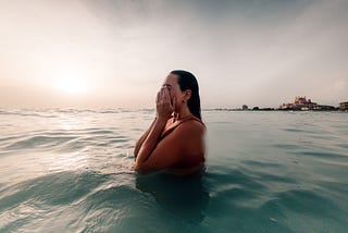 A girl in water during sunset at the beach.