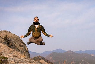 Man appearing to levitate above a mountain.