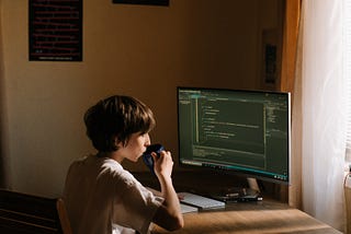 A boy doing coding while drinking coffee