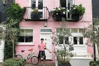 A boy in pink and black stands in front of a matching pink and black house with open arms. His name is Cole Tretheway.