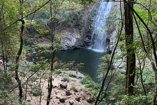 Aerial, woman standing under waterfall in Montezuma, Costa Rica