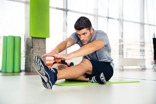 man stretching on the floor at a gym