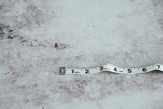 A measuring tape lying on a textured surface, showing inches.