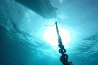 View of an anchor chain leading to a boar from underwater