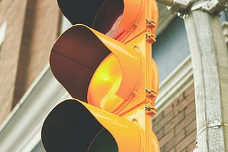 the photo shows a traffic signal with the yellow light lit, signaling caution.