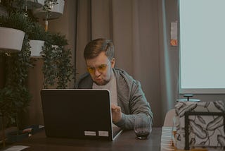Man thinking hard while typing out his wife’s reviews on the computer.