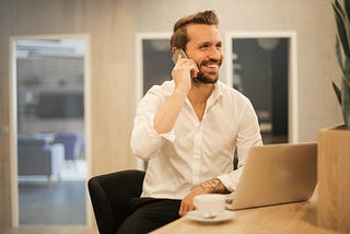 A businessman in business attire busily takes a phone call.